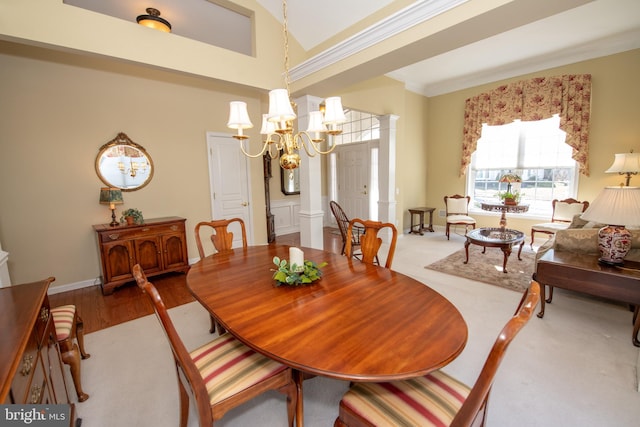 dining room with a chandelier, crown molding, ornate columns, and wood finished floors