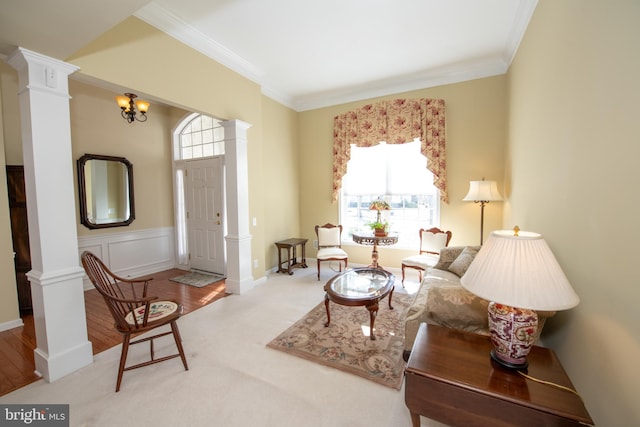 carpeted living room with a wealth of natural light, a wainscoted wall, crown molding, and ornate columns