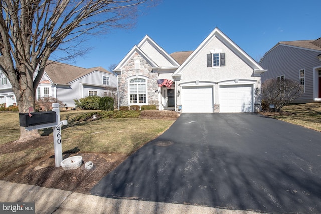 view of front of property featuring aphalt driveway, stone siding, a front lawn, and an attached garage