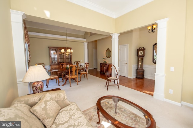 living area featuring a notable chandelier, carpet floors, crown molding, baseboards, and ornate columns