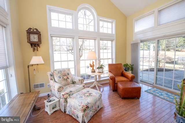 sitting room featuring visible vents, wood-type flooring, high vaulted ceiling, and baseboards