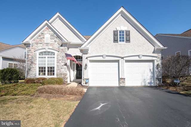 view of front of home featuring aphalt driveway, stone siding, and stucco siding