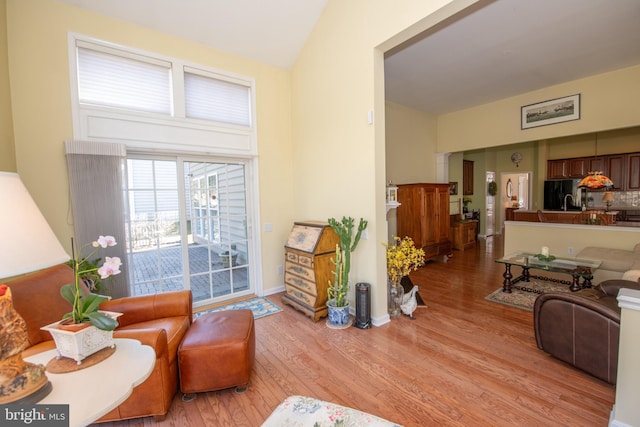 interior space featuring light wood-type flooring, baseboards, and vaulted ceiling