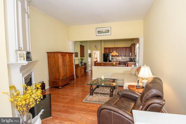 living area featuring a fireplace, light wood-type flooring, and baseboards