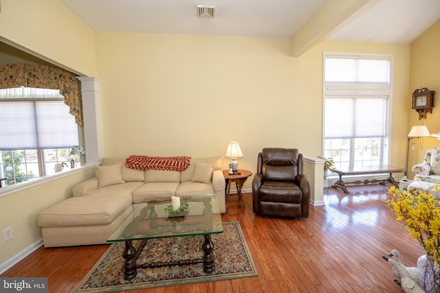 living room featuring baseboards, wood finished floors, visible vents, and a healthy amount of sunlight