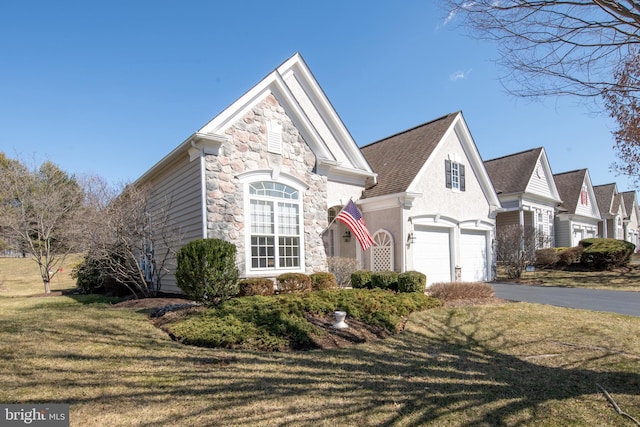 view of front of home with aphalt driveway, stone siding, a front lawn, and an attached garage