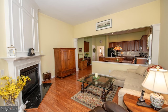 living area with decorative columns, a fireplace, and light wood finished floors