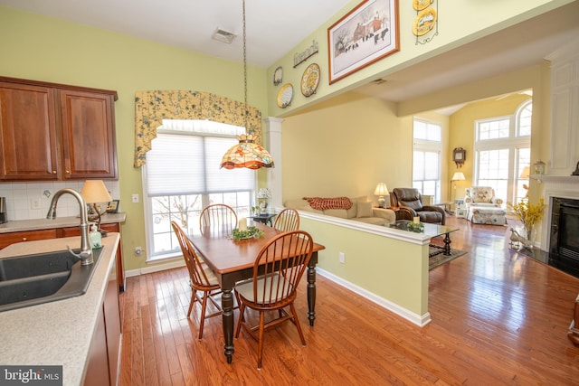 dining space with a wealth of natural light, visible vents, light wood-type flooring, and a fireplace with flush hearth