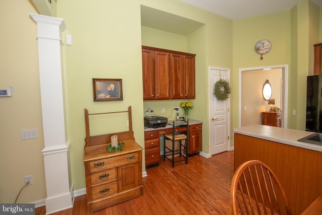 kitchen with light wood finished floors, baseboards, light countertops, and ornate columns