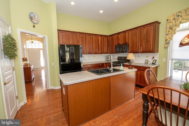 kitchen with decorative backsplash, light wood-style floors, black appliances, and light countertops