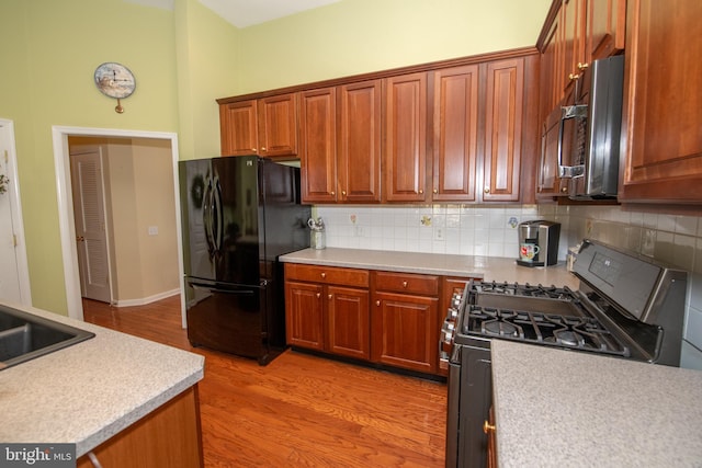 kitchen featuring light wood-type flooring, tasteful backsplash, appliances with stainless steel finishes, and light countertops