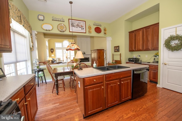 kitchen featuring dishwasher, light countertops, decorative columns, light wood-style flooring, and a sink