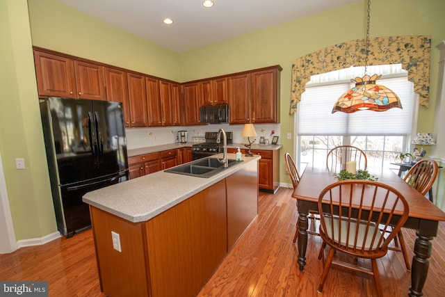 kitchen with black appliances, light countertops, light wood-type flooring, and a sink