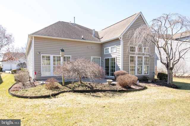 rear view of house with a yard and a shingled roof