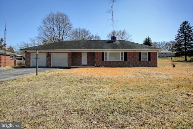 ranch-style house with aphalt driveway, an attached garage, brick siding, and a front lawn