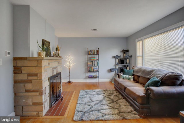 living room featuring visible vents, baseboards, wood finished floors, and a fireplace