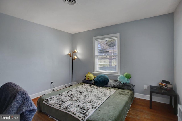 bedroom with visible vents, baseboards, and wood finished floors