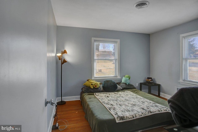 bedroom featuring visible vents, baseboards, and wood finished floors