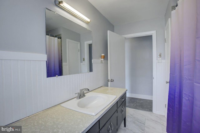 full bathroom featuring vanity, marble finish floor, and wainscoting