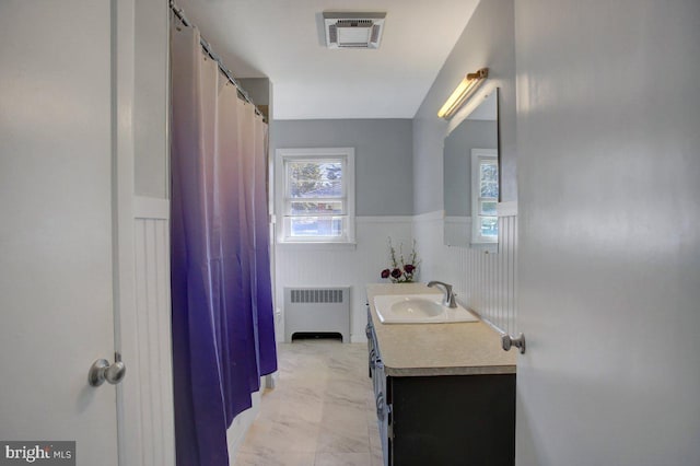 bathroom featuring visible vents, plenty of natural light, radiator, wainscoting, and vanity