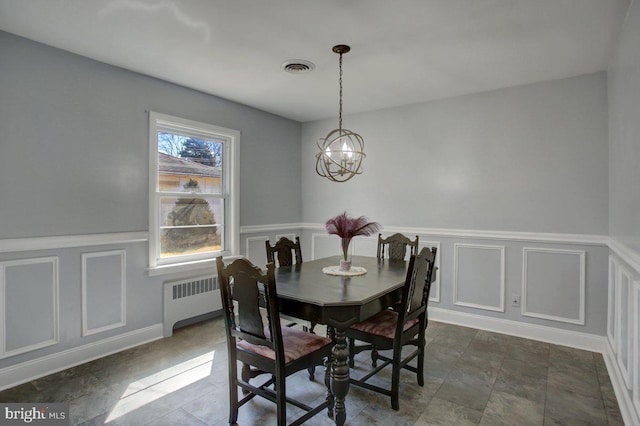 dining area with visible vents, radiator heating unit, an inviting chandelier, wainscoting, and a decorative wall