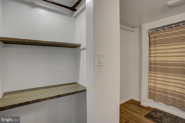 walk in closet featuring visible vents, built in desk, and wood finished floors