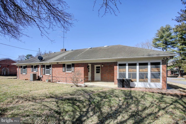 rear view of property featuring brick siding, central AC unit, a lawn, a chimney, and a patio