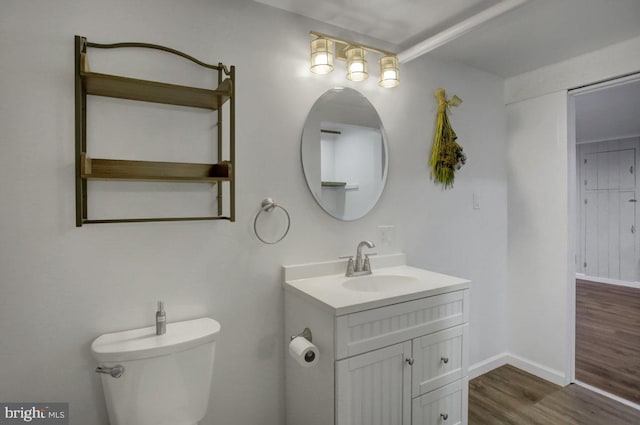 bathroom with vanity, toilet, wood finished floors, and baseboards