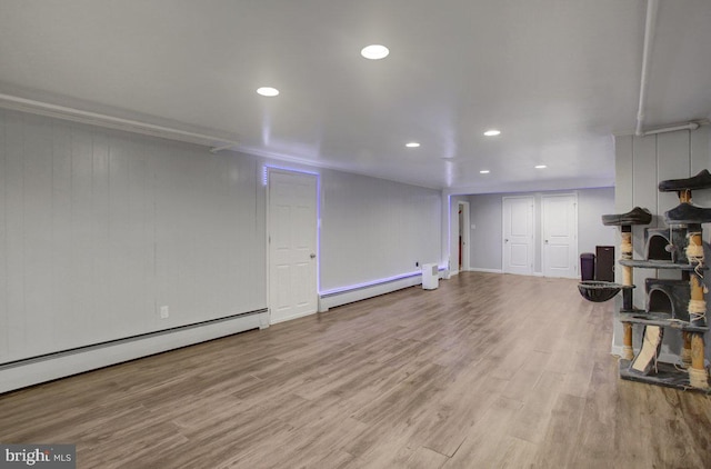 finished below grade area with recessed lighting, a baseboard radiator, baseboard heating, and wood finished floors