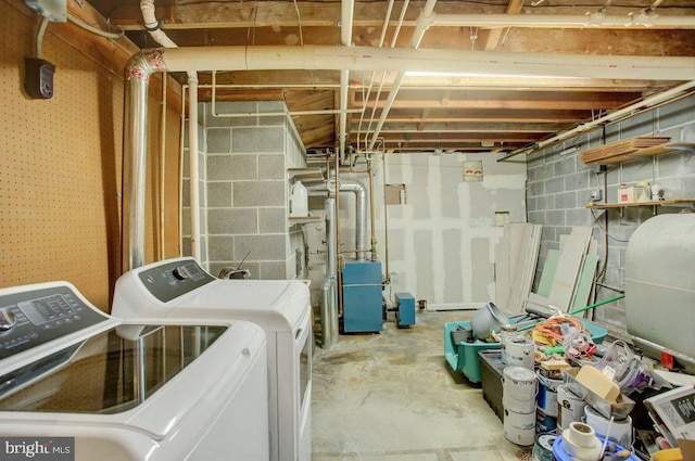 unfinished below grade area featuring heating fuel, concrete block wall, and separate washer and dryer