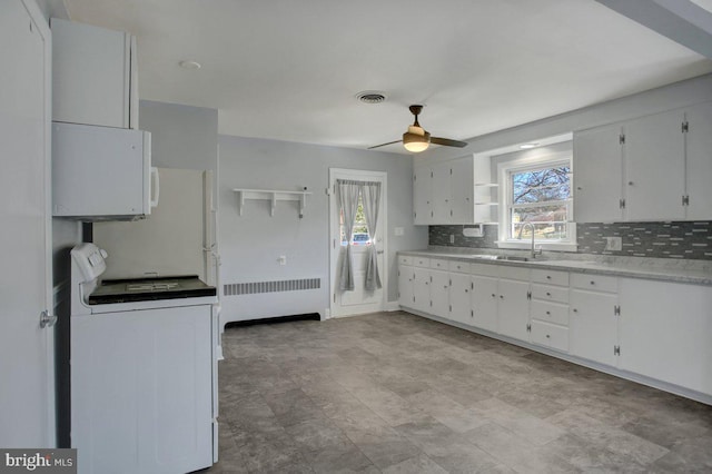 kitchen with visible vents, washer / dryer, radiator heating unit, a sink, and a wealth of natural light