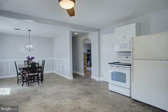 kitchen featuring decorative light fixtures, white appliances, arched walkways, white cabinets, and a decorative wall