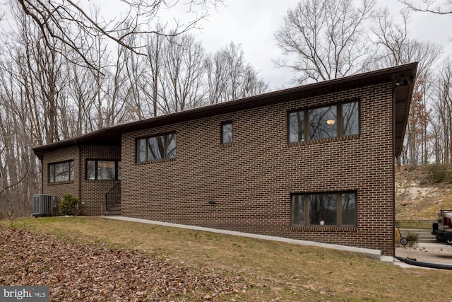 exterior space featuring a front lawn, cooling unit, and brick siding