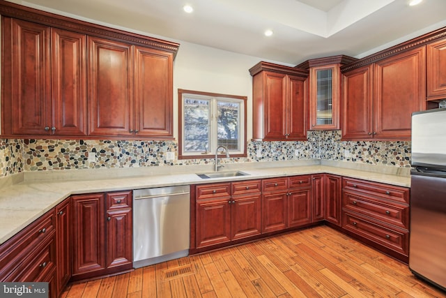 kitchen featuring a sink, tasteful backsplash, stainless steel appliances, light wood-style floors, and dark brown cabinets