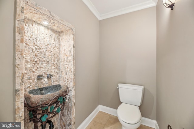 half bathroom with tile patterned flooring, baseboards, toilet, ornamental molding, and vanity