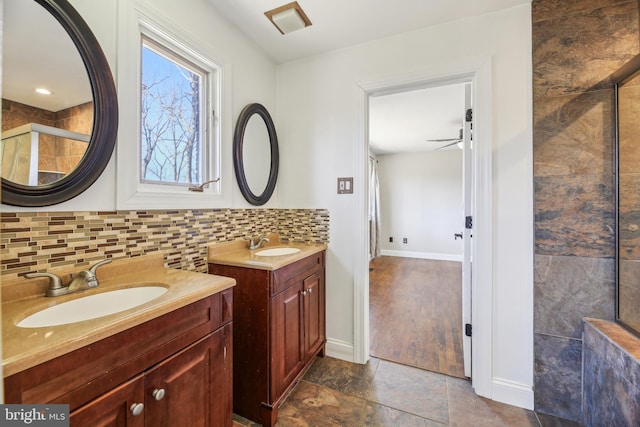 bathroom featuring decorative backsplash, two vanities, ceiling fan, and a sink