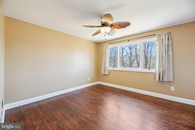 spare room featuring a ceiling fan, visible vents, baseboards, and wood-type flooring