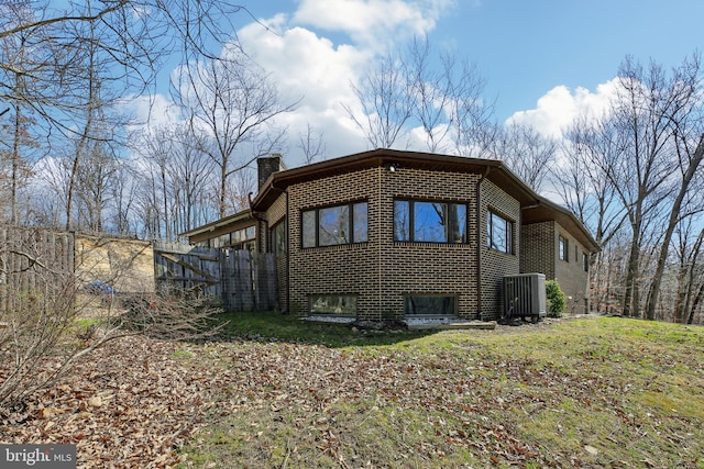 exterior space featuring brick siding, a lawn, a chimney, and fence