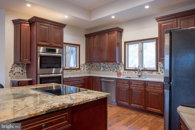 kitchen with backsplash, light wood-style floors, appliances with stainless steel finishes, and a sink