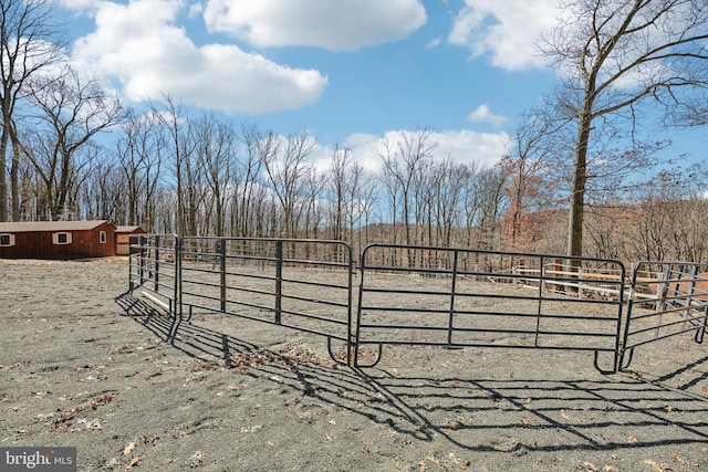 view of gate with an outbuilding, a rural view, and fence