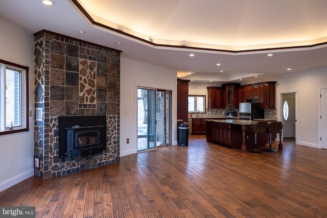 kitchen featuring dark wood-style floors, a breakfast bar, a tray ceiling, light countertops, and backsplash