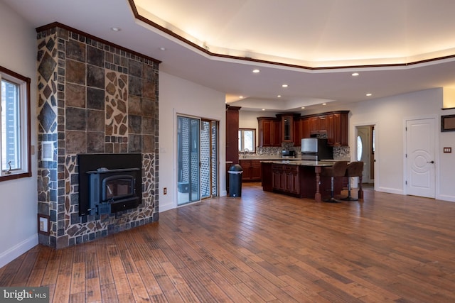 kitchen featuring a tray ceiling, dark wood-style flooring, freestanding refrigerator, light countertops, and a kitchen bar