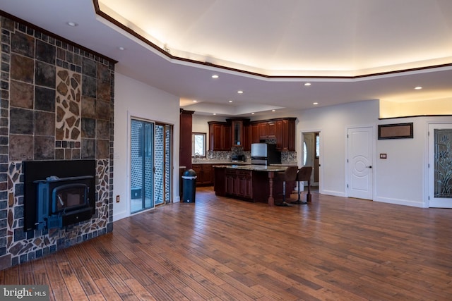 kitchen featuring a kitchen island, dark wood finished floors, light countertops, a raised ceiling, and a kitchen breakfast bar