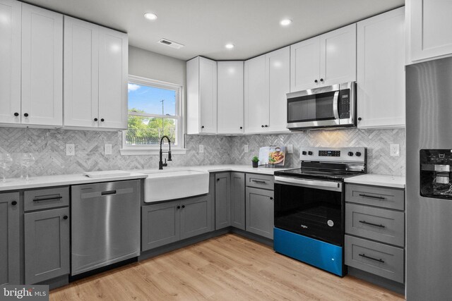 kitchen featuring visible vents, gray cabinetry, stainless steel appliances, and a sink