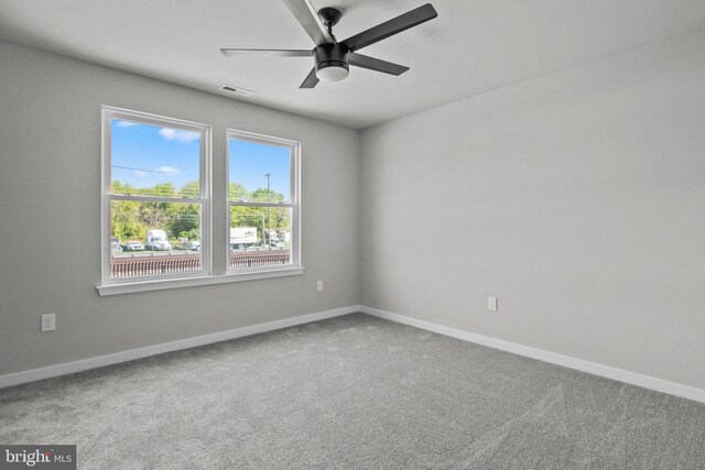 carpeted spare room with a ceiling fan, baseboards, and visible vents