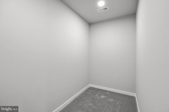 interior space featuring baseboards, visible vents, and dark carpet