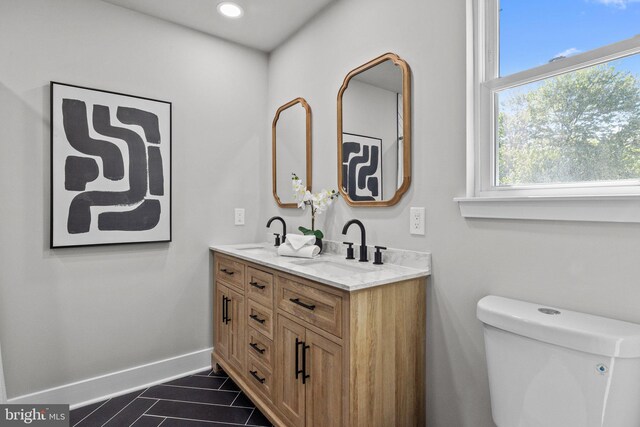 bathroom featuring double vanity, baseboards, tile patterned floors, and a sink