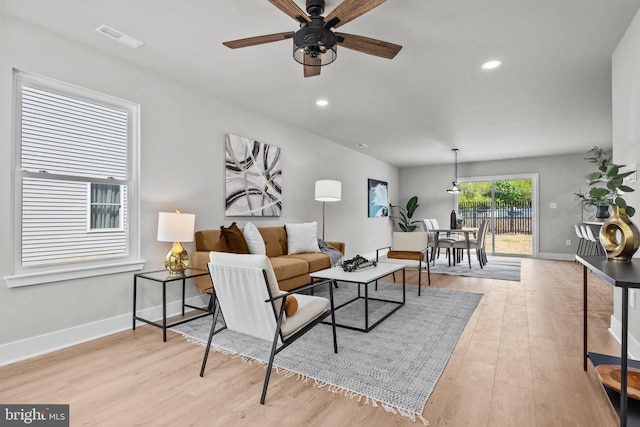 living area with recessed lighting, visible vents, baseboards, and light wood finished floors