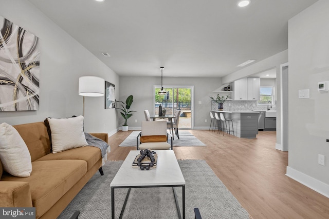 living room with recessed lighting, visible vents, baseboards, and light wood finished floors