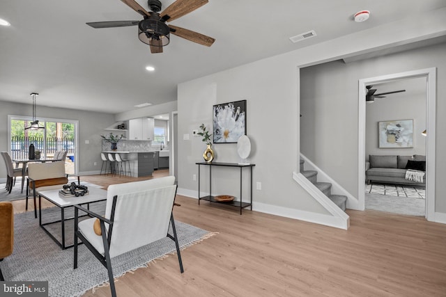 living area with baseboards, visible vents, recessed lighting, stairs, and light wood-type flooring